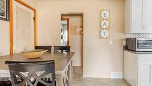 Un comedor con una mesa y sillas, una cocina con armarios, y una pared con las letras