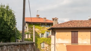 A narrow cobblestone street flanked by stone walls and buildings with red-tiled roofs. - Aperol in Iseo With 1 Bedrooms and 1 Bathrooms (Iseo)