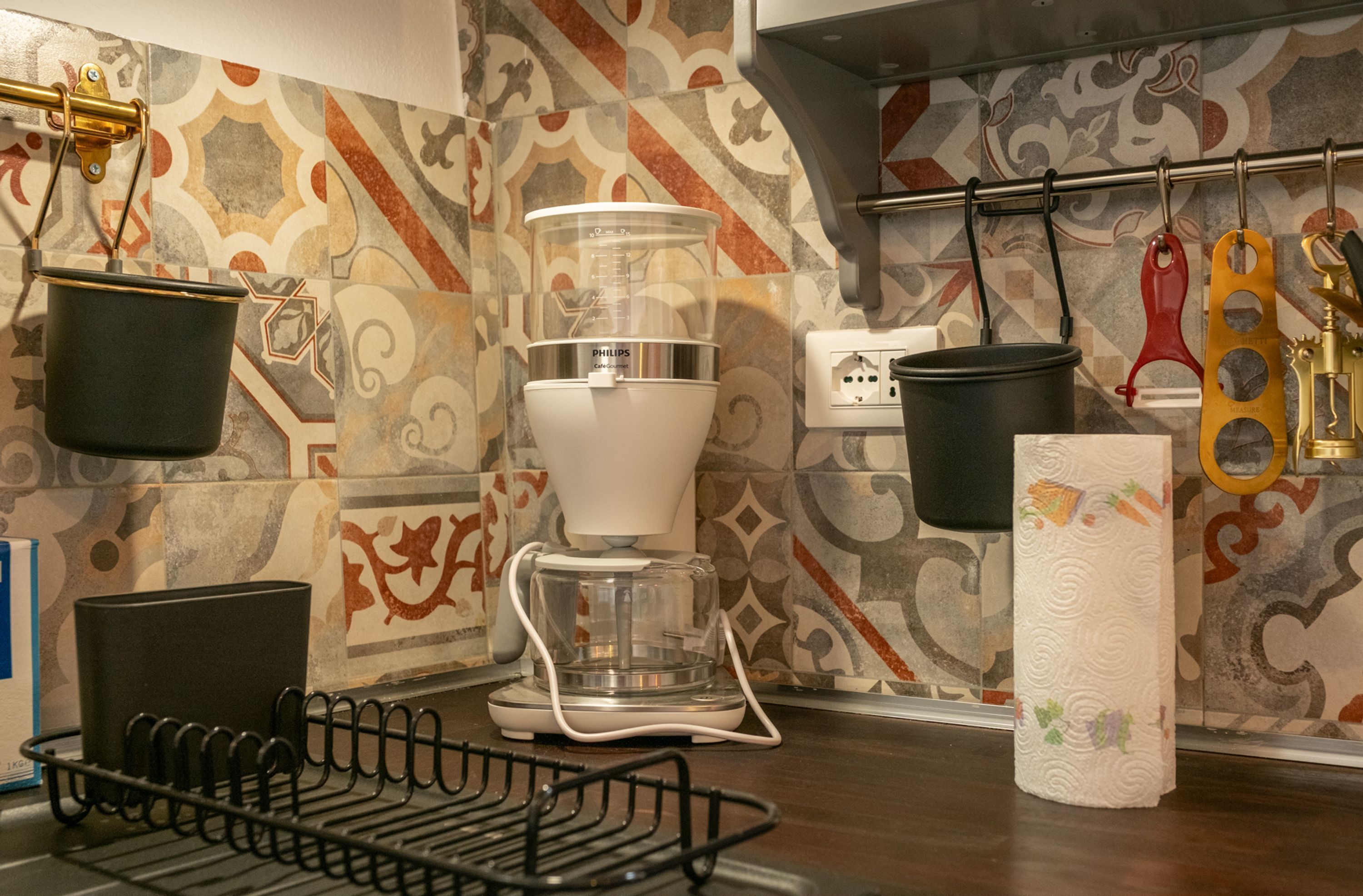 Une cuisine équipée d’une machine à café, de casseroles suspendues et d’un porte-essuie-tout.