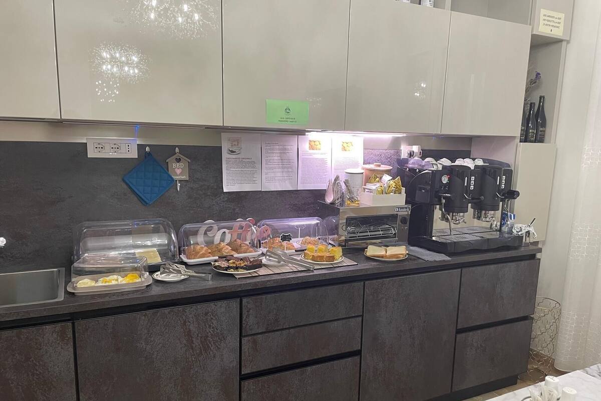 Een ontbijtbuffet met diverse etenswaren, een koffieapparaat en een bord waarop de ontbijttijden staan.
