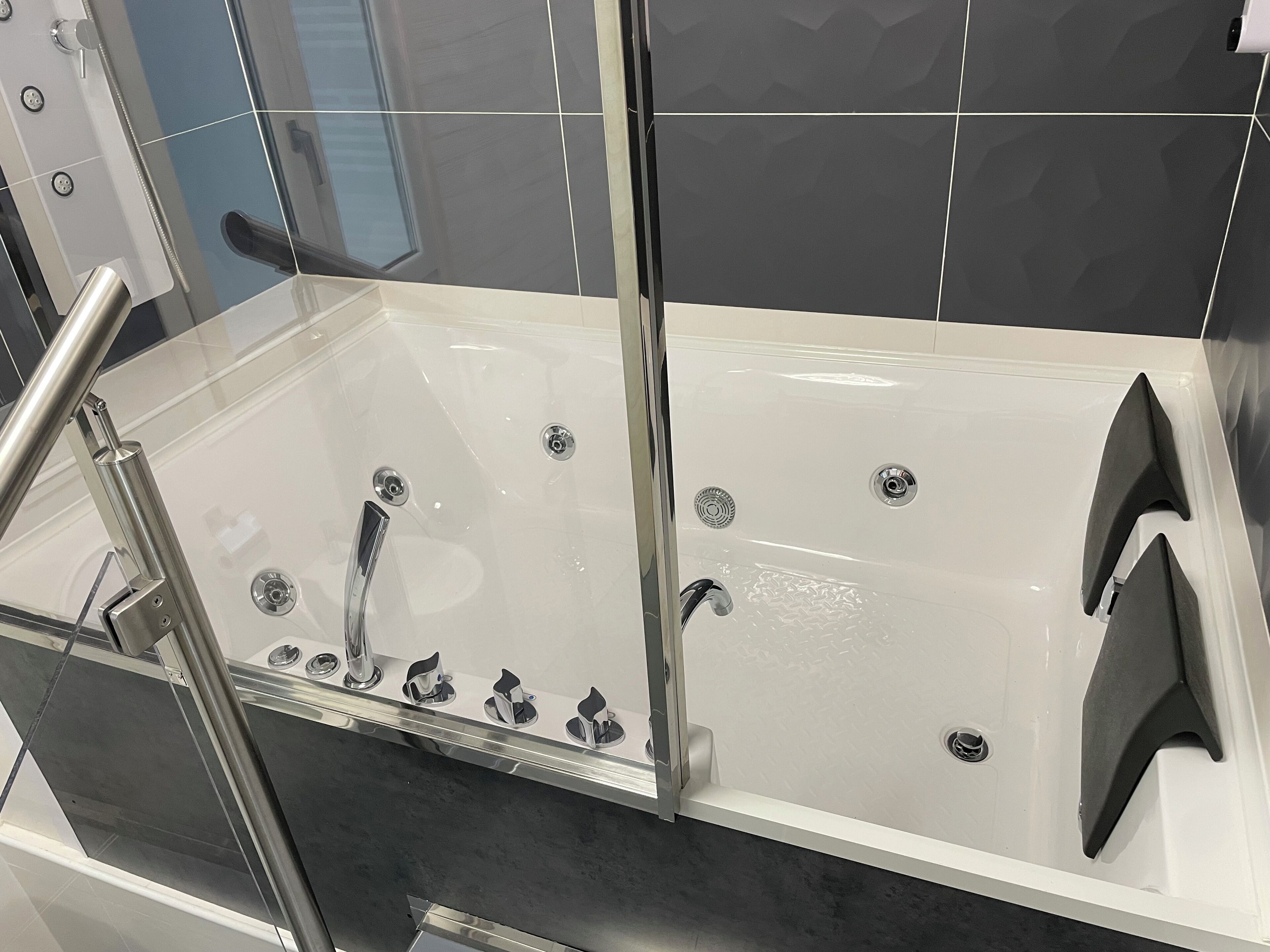 Ein modernes Badezimmer mit einer Glaskabine zur Badewanne, einer separaten Duschkabine und einem WC.