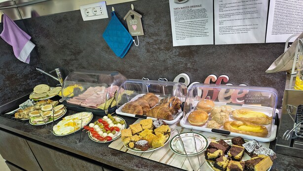 Un buffet proposant une variété de plats, notamment des sandwichs, des pâtisseries et des desserts, présentés dans des récipients transparents.