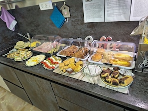 A buffet counter with various food items, including sandwiches, pastries, and desserts, displayed in clear containers. - B & B VERDE NATURA (Spilamberto)