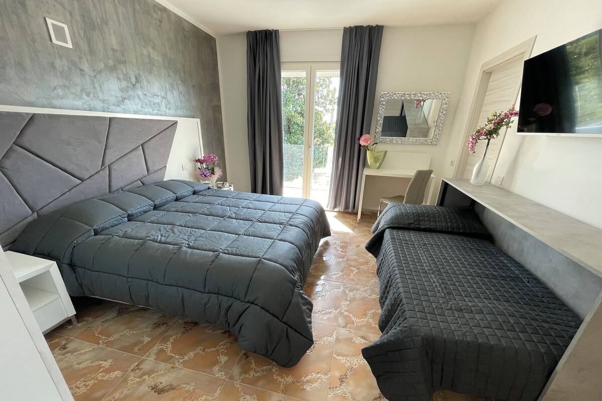 Een moderne slaapkamer met een groot bed, een slaapbank en een bureau.