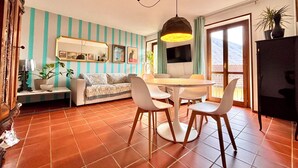 A living room with a sofa, dining table, chairs, and a TV. - Oh!megna in the historic heart (Omegna)
