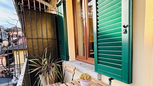 A balcony with wooden benches and a potted plant, featuring green shutters and a view of the city. - Oh!megna in the historic heart (Omegna)