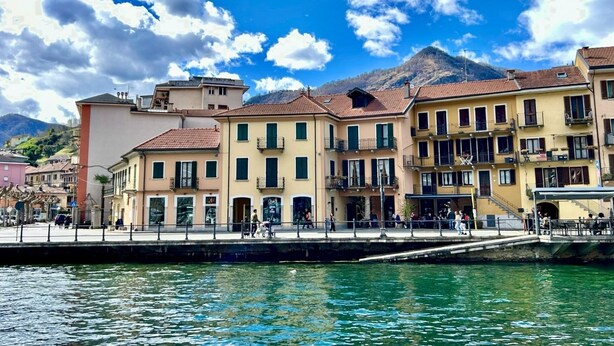 A waterfront building with balconies, a dock, and a mountain in the background. - Oh!megna in the historic heart (Omegna)