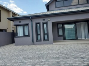 Stylish two-story building with a flat roof and covered outdoor area, featuring a large sliding glass door and symmetrical design.