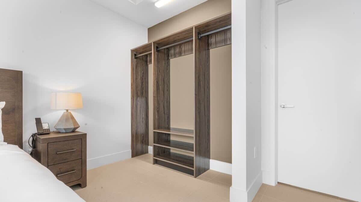 Une chambre à coucher comprenant un lit, une table de chevet avec une lampe, une armoire avec plusieurs étagères et une porte.