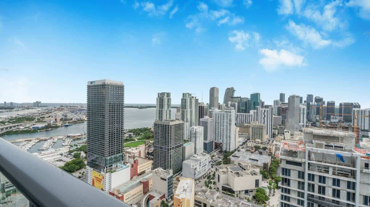 A high-rise building with a modern architectural design, surrounded by other high-rise buildings and a body of water in the background.