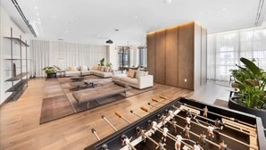 A spacious, modern lobby with a seating area, a foosball table, and large windows allowing natural light. - Lux 2BR Condo With Pool, Spa & Gym Access (Miami)