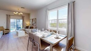 A modern living room with a dining area, large windows, and a view of the city. - 5BR Villa w/ Pvt Pool, 15 Min to Disney, Sleeps 10 (Davenport)