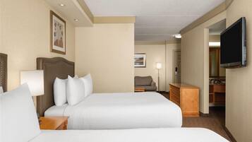 A hotel room with two beds, a TV, a desk, and a chair.