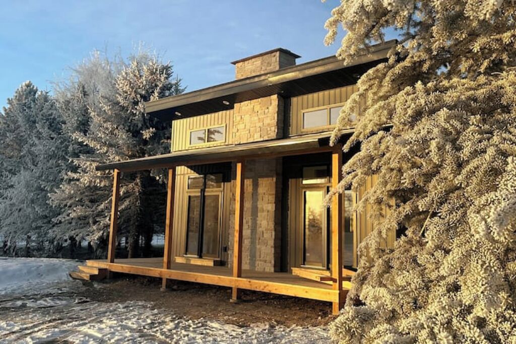 A modern two-story house with large windows and a wooden deck.
