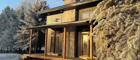 A modern two-story house with large windows and a wooden deck.
