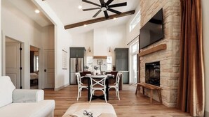 Un salón amplio con chimenea, un comedor con mesa y sillas, y una cocina al fondo.