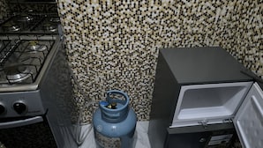 A kitchen with a gas stove, a gas cylinder, and a refrigerator. - SOTIDEK YOP (Abidjan)