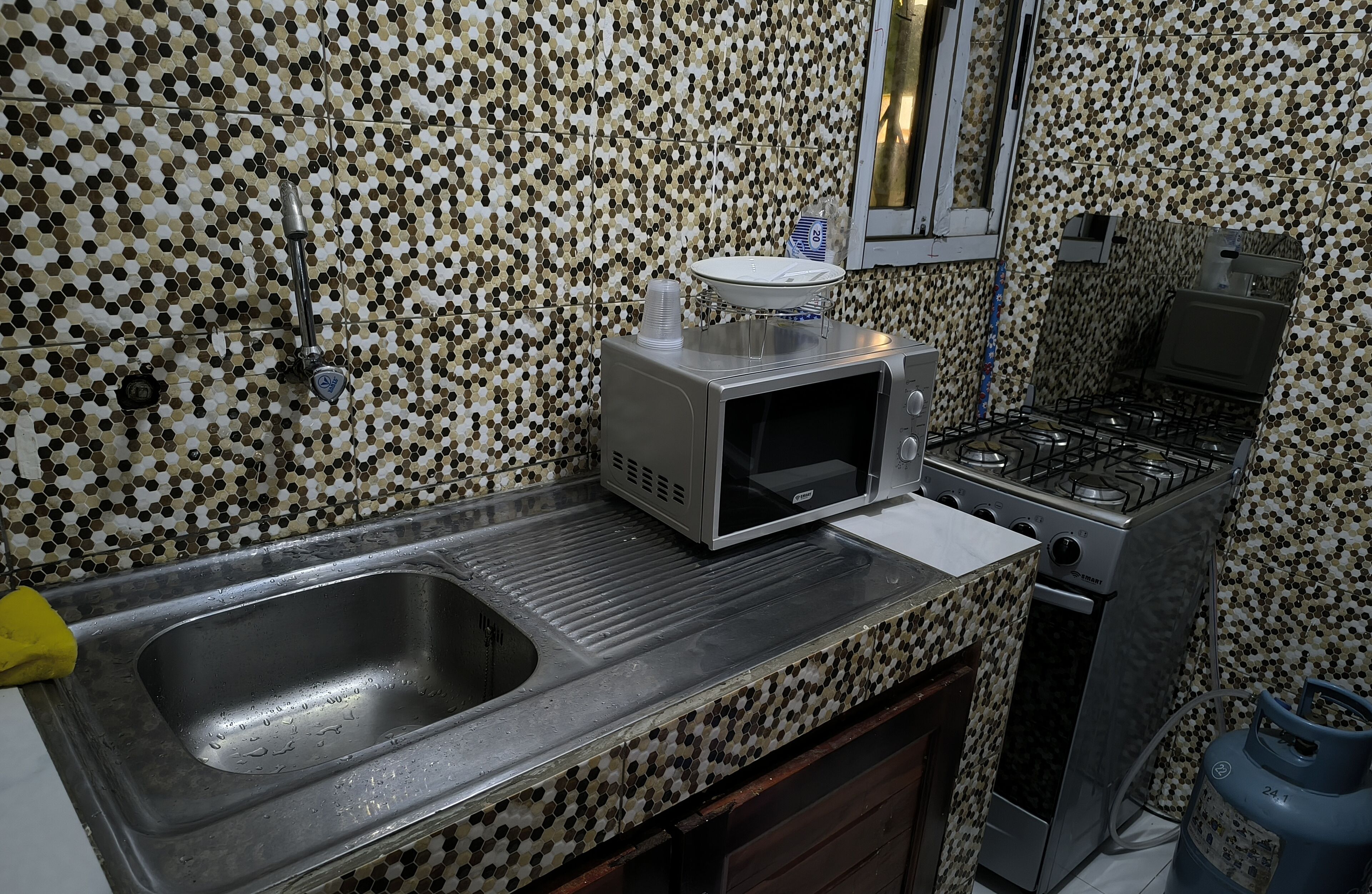 A kitchen with a microwave, stove, sink, and tiled backsplash.