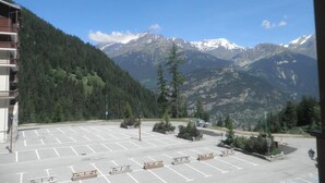 A parking lot with marked spaces, a building with balconies, and a mountain view.