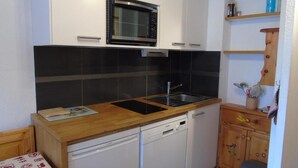 A compact kitchen with a built-in microwave, a sink, and a dishwasher.