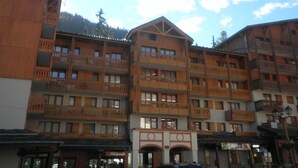 A multi-story hotel with wooden balconies and a ski resort backdrop.