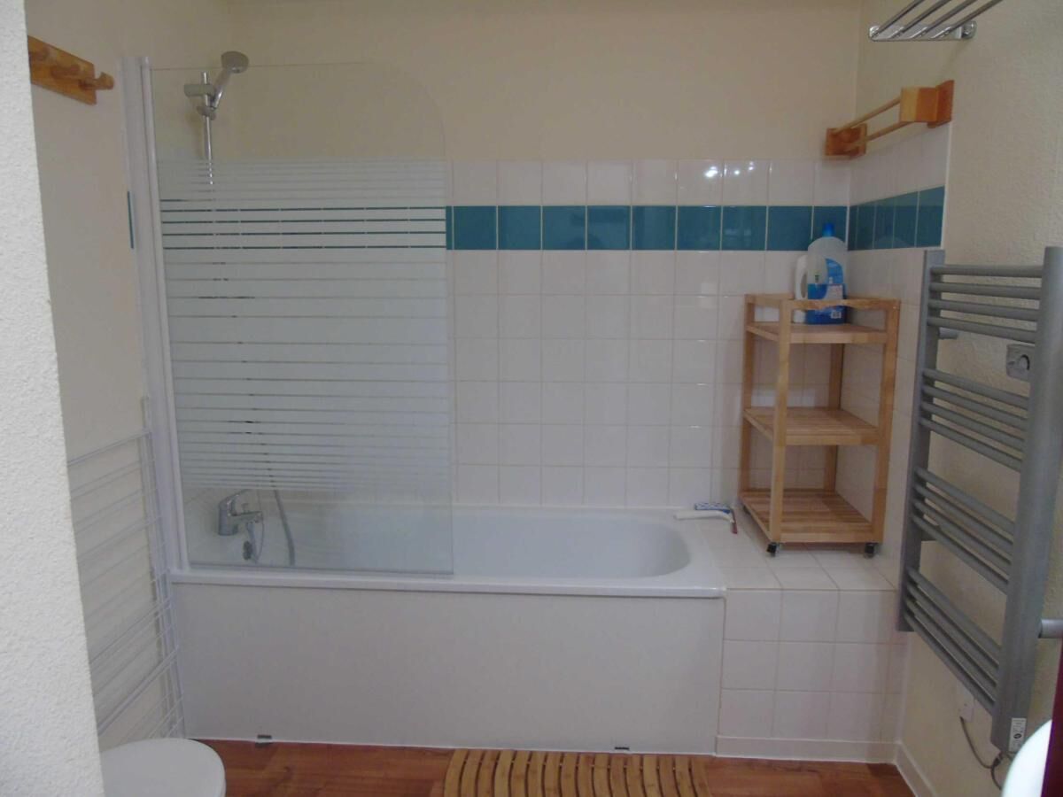 A bathroom with a bathtub, a shower, and a wooden shelf unit.