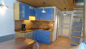 A compact kitchen with blue cabinets, a wooden countertop, and a brick backsplash.