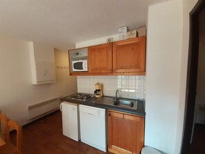 A compact kitchen with a microwave, stove, sink, and dishwasher.