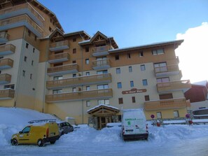 A multi-story hotel with balconies, a covered entrance, and a snow-covered ground.