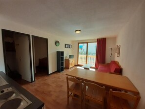 A compact living space with a kitchenette, a dining area, and a balcony with a red curtain. - 5th floor, view resort, balcony, tv, ski locker, 36m², Valfréjus (Valfréjus)