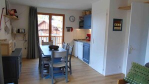 Una cocina compacta con comedor, piso de madera y vistas por una puerta corrediza.