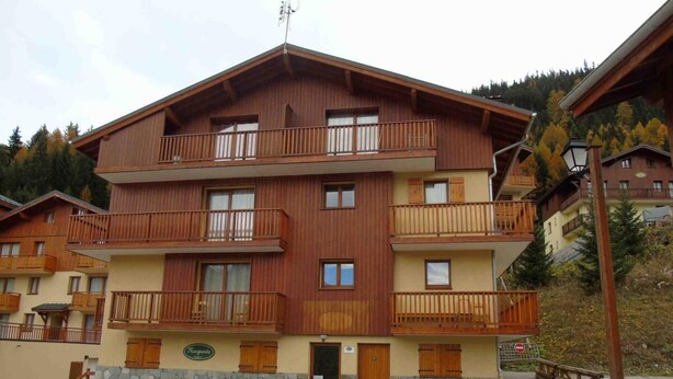 Un edificio de madera de varios pisos con balcones, cimientos de piedra y un letrero que indica que es un hotel.