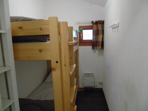 Camera con letto a castello, finestra, termosifone e tenda.