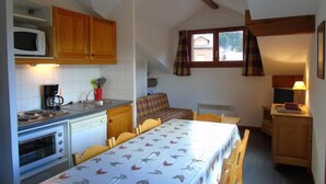 A compact kitchen with a dining table, a microwave, a coffee maker, and a small oven.