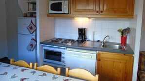 A compact kitchen with a microwave, stove, oven, and sink.