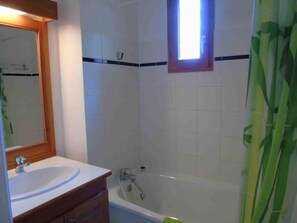 A bathroom with a white sink, wooden vanity, a mirror, a bathtub, and a window. - 1st floor, view mountain, balcony, tv, ski locker, 48m², Valfréjus (Valfréjus)