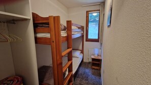 Een slaapkamer met een stapelbed, een radiator en een raam.