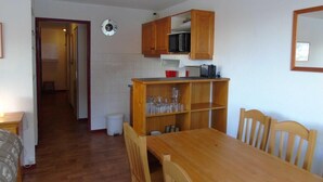 A compact kitchen with wooden cabinets, a microwave, and a dining table with chairs. - 2nd floor, view valley, balcony, tv, ski locker, 61m², Valfréjus (Valfréjus)