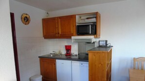 A compact kitchen with wooden cabinets, a microwave, a dishwasher, and a red coffee maker. - 2nd floor, view valley, balcony, tv, ski locker, 61m², Valfréjus (Valfréjus)