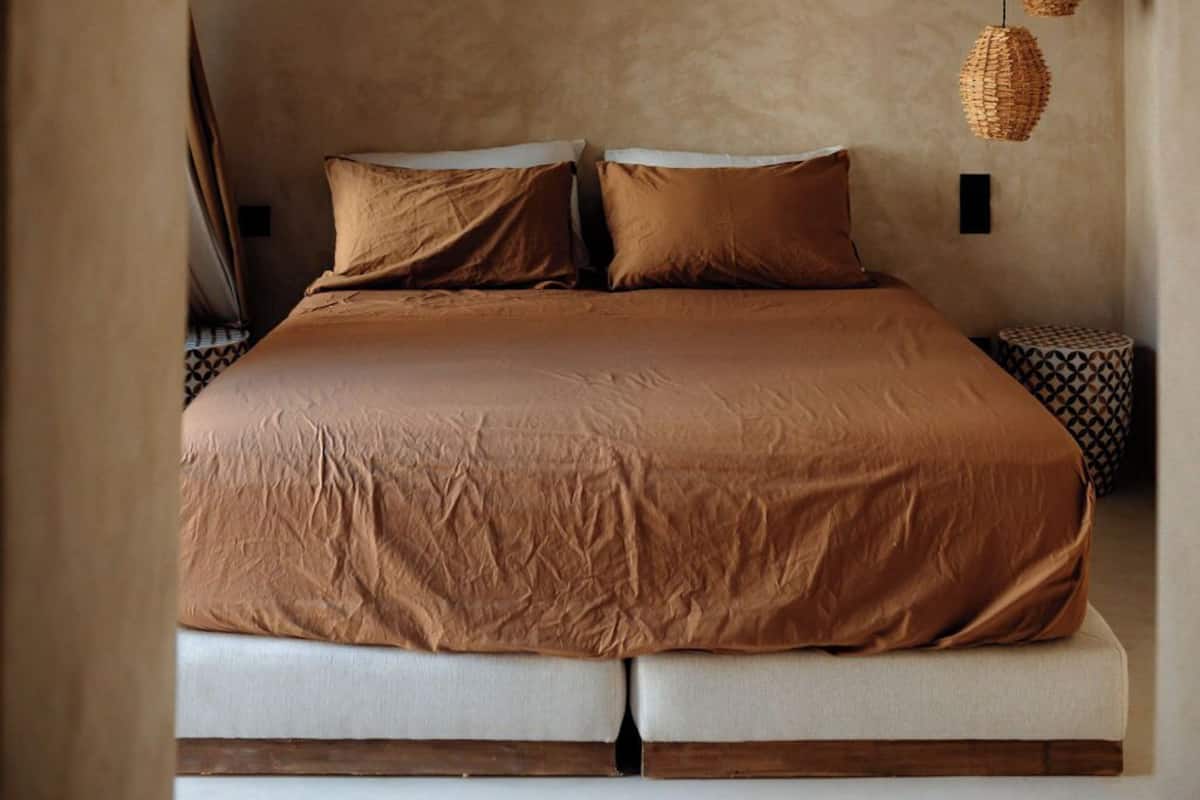 A bedroom with a bed, a ceiling fan, and hanging woven light fixtures.