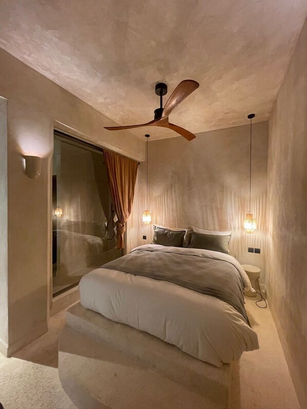 A bedroom with a bed, a ceiling fan, and wall-mounted lights.