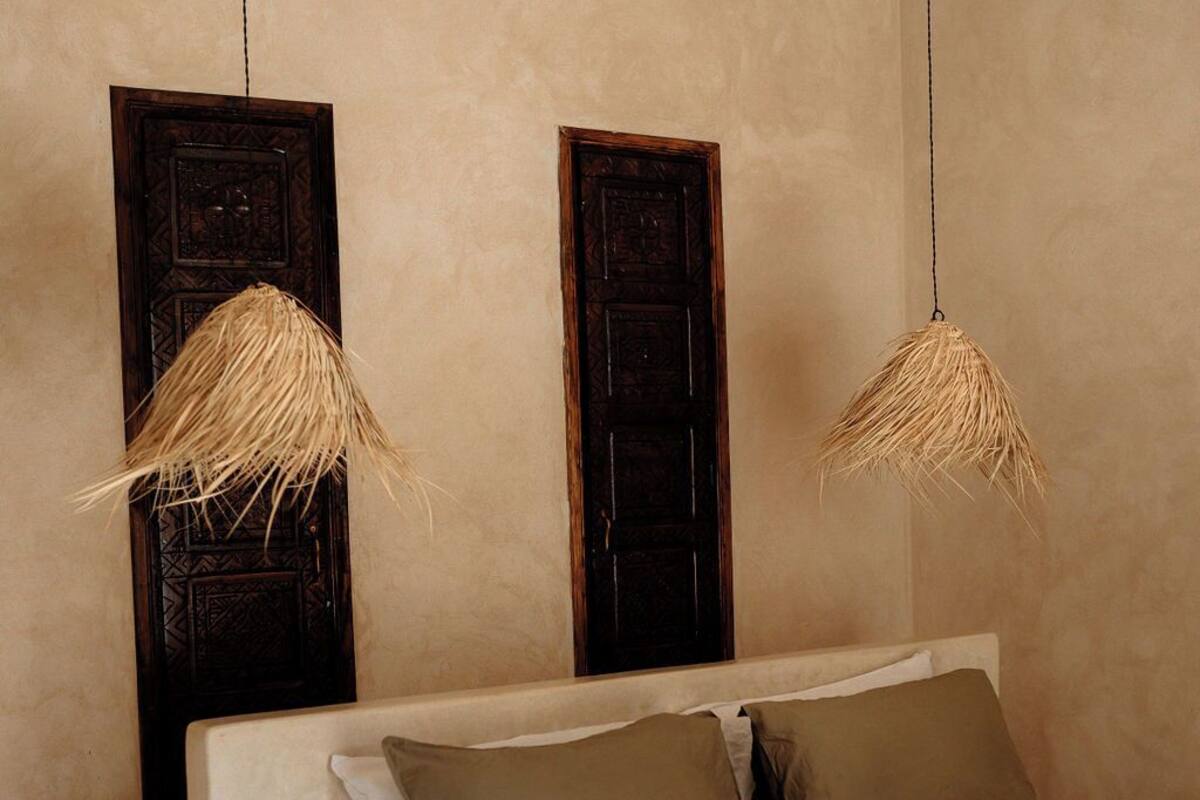 A bedroom with a bed, two wooden doors, and two hanging light fixtures.