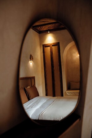 A circular view of a bedroom with a bed, a nightstand, a wall-mounted light, and a wooden door.