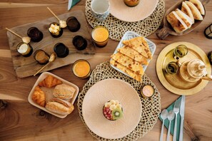 A breakfast setting with croissants, pastries, and a variety of drinks on a wooden table.