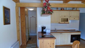 A compact kitchen with wooden cabinets, a built-in oven, and a coffee maker. - 8th floor, view resort, balcony, tv, ski locker, 76m², Valfréjus (Valfréjus)