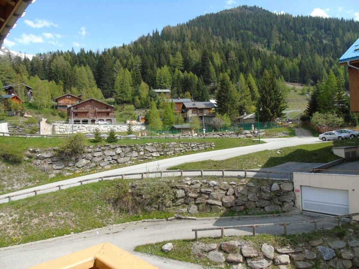A mountain village with stone walls, wooden houses, and a winding road.