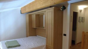 A bedroom with a single bed, a wooden wardrobe, and a mirror above the bed. - 8th floor, view resort, balcony, tv, ski locker, 76m², Valfréjus (Valfréjus)