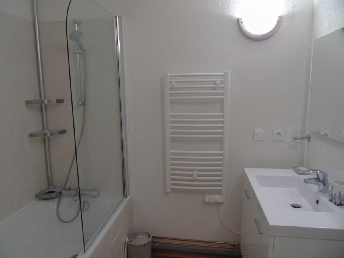 A bathroom with a glass-enclosed shower, a white sink, and a mirror above the sink.