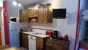 A compact kitchen with wooden cabinets, a microwave, a stove, and a small sink.