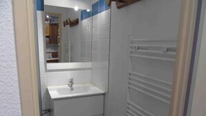 A small bathroom with a white sink, mirror, and white towel rack.